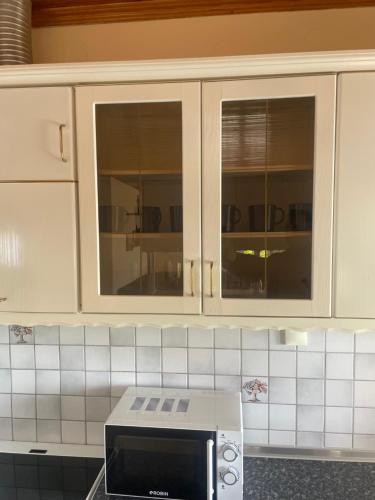 uma cozinha com armários brancos e um micro-ondas em Hοme4U em Kallikrateia