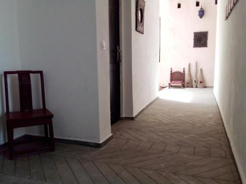 a hallway with a chair and a wooden floor at Cytyz Appart Hôtel in Mahajanga