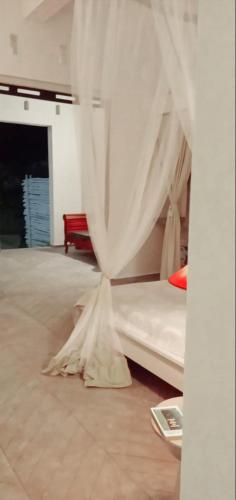 a bedroom with a bed with white curtains at Cytyz Appart Hôtel in Mahajanga