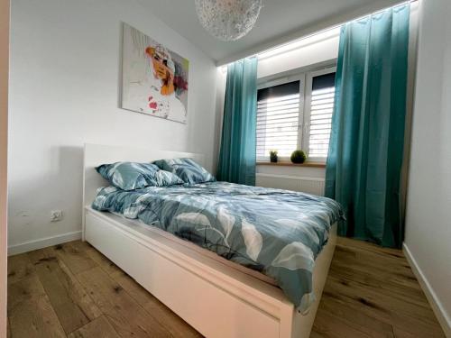 a bedroom with a bed with blue curtains and a window at Apartament Termalny in Uniejow