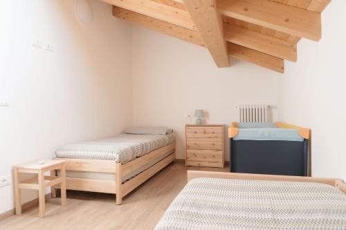 two beds in a room with wooden floors and wooden ceilings at Casa ALMA in Colico