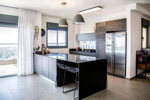 a kitchen with a stainless steel refrigerator and a counter at A large and well-designed apartment with a stunning view in Or ‘Aqīvāh