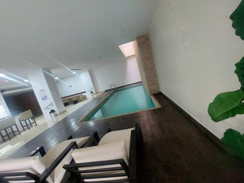 una piscina en una habitación con sillas y mesa en CORAL SUITE CON VISTA CIUDAD/PISCINA, GYM, PARQUEO, en Guayaquil