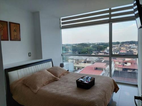 a bedroom with a bed and a large window at CORAL SUITE CON VISTA CIUDAD/PISCINA, GYM, PARQUEO in Guayaquil