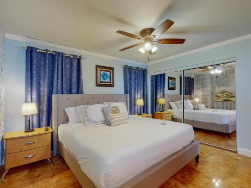 a bedroom with a bed with a ceiling fan and a mirror at MP217 Gulf view condo with Boardwalk to Beach in Padre Island