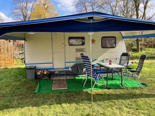 a caravan with a blue roof and a table and chairs at De kastanjehof 31 in Beerta