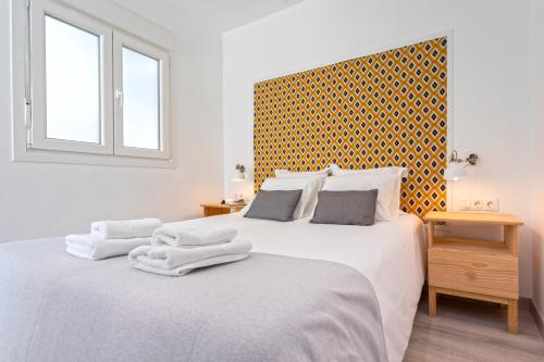 Habitación blanca con 2 camas y toallas. en Livemalaga Pedregalejo, en Málaga