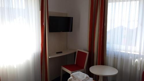 ノルデンにあるHotel & Restaurant Möwchenの赤い椅子、テーブル、テレビが備わる客室です。