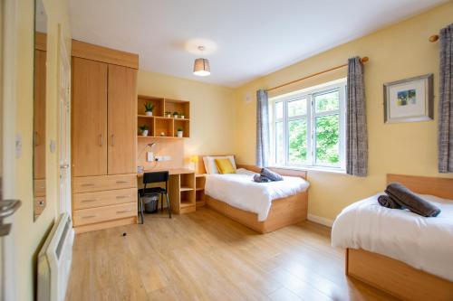a bedroom with two beds and a desk and a window at City Center 4 Bedroom Townhouse - Sleeps 8 in Galway