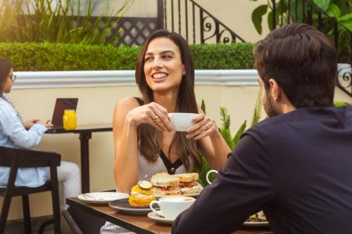 a woman sitting at a table with a cup of coffee at Country Club Lima Hotel – The Leading Hotels of the World in Lima