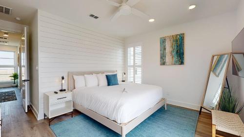 a white bedroom with a bed and a ceiling fan at Dorado Dunes #D Newly Built, Gorgeous Beach Home, Private Pool, Golf Cart Entire Stay in Port Aransas