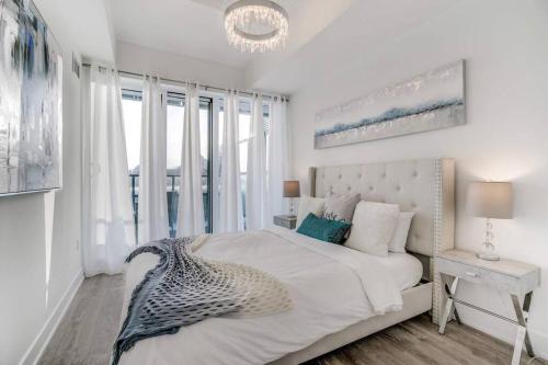 a white bedroom with a bed with a large window at Waterfront Luxury Condo in Toronto