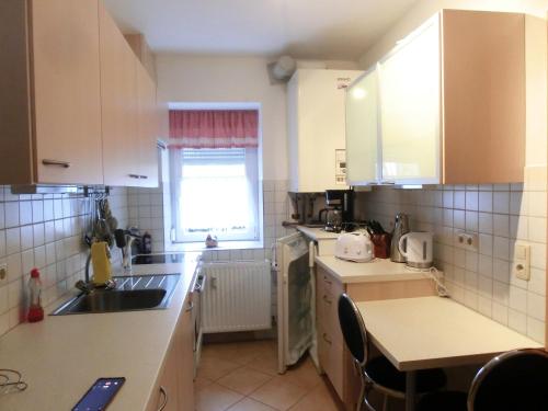 d'une cuisine avec des placards blancs, un évier et une fenêtre. dans l'établissement Haus Peter, à Eppendorf