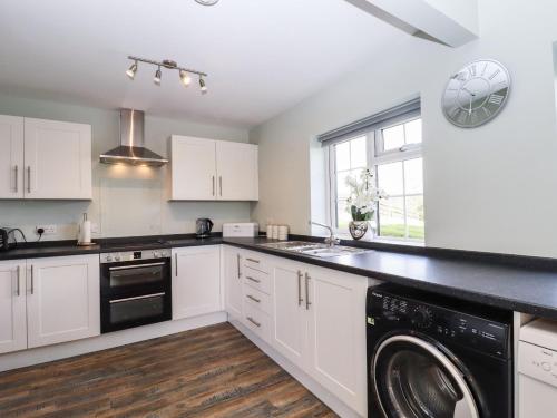 a kitchen with white cabinets and a washer and dryer at Orchard Retreat in Paddock Wood