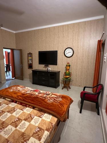 a bedroom with a bed and a clock on the wall at Kaashi Flora (Full Villa - 5 Bedrooms) in Varanasi