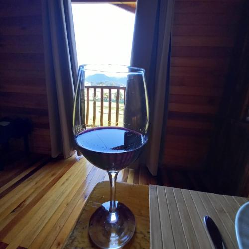 a glass of red wine sitting on a table at Pousada Cabanas Xokleng in Urubici