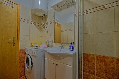 a bathroom with a sink and a washing machine at Apartmani Vila Nela in Postira
