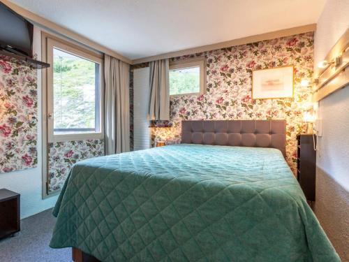 - une chambre avec un lit doté d'un couvre-lit vert dans l'établissement Agréable 2P skis aux pieds avec parking couvert - FR-1-694-220, à Val dʼIsère