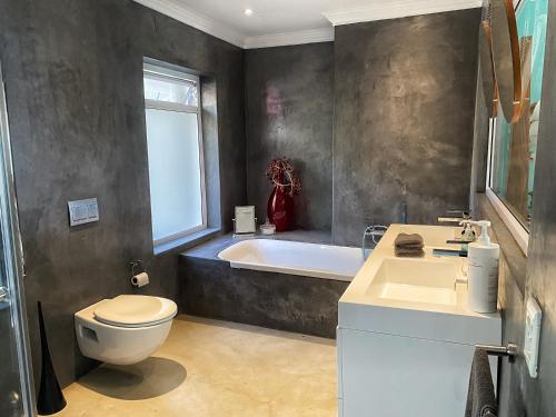 a bathroom with a toilet and a tub and a sink at Residence William French in Simonʼs Town