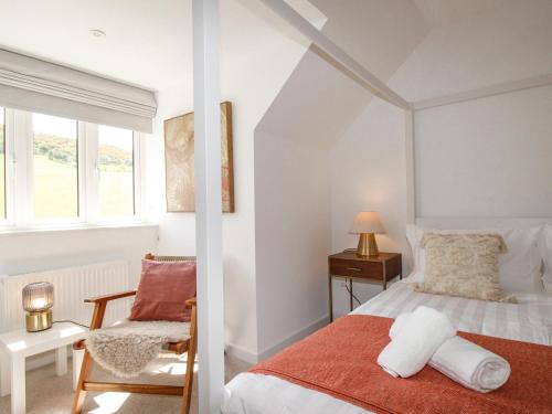 a bedroom with a bed and a chair and a window at Waterston Cottage in Wareham