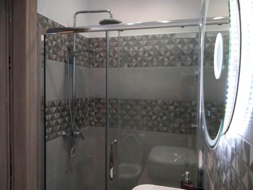 una ducha con una puerta de cristal junto a un lavabo en Nisos suite en Ermúpoli