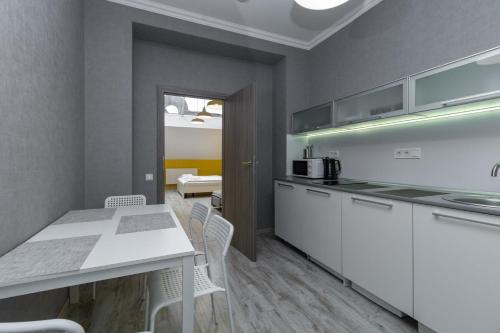 a kitchen with white cabinets and a table and chairs at Opera Passage Hotel & Apartments in Lviv