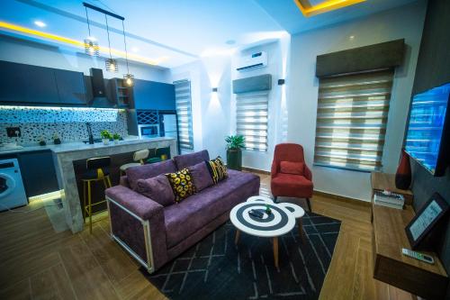 a living room with a purple couch and a kitchen at Hortencia by Durudove Apartments in Kubwa