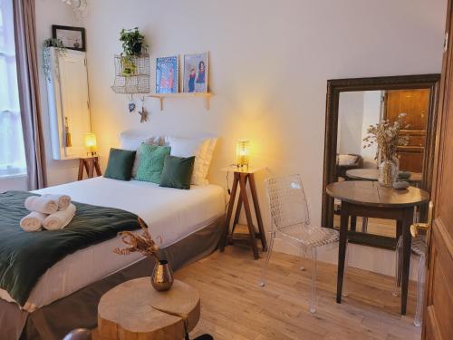 een slaapkamer met een bed, een tafel en een spiegel bij My Little Garden -Parking gratuit 500m -Coeur historique -La Clef de Honfleur in Honfleur