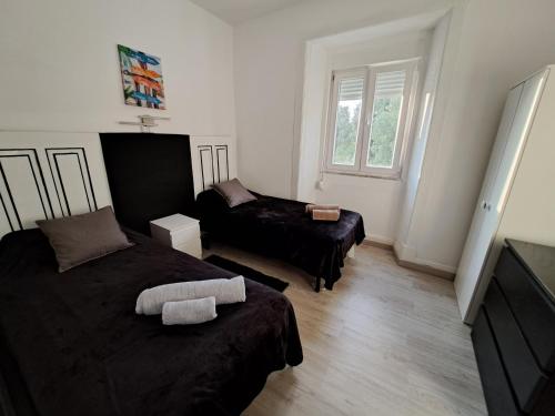 um pequeno quarto com 2 camas e uma janela em Guest dAires em Coimbra