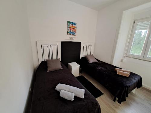 um quarto com 2 camas com lençóis pretos e uma janela em Guest dAires em Coimbra