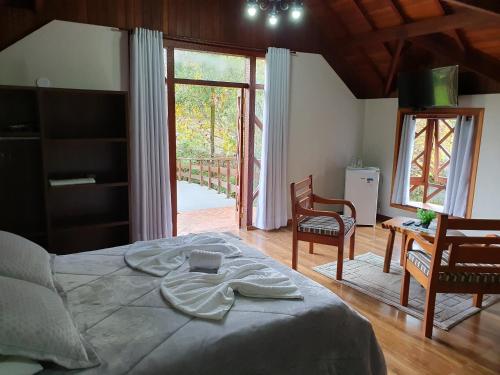 um quarto com uma cama, uma mesa e cadeiras em Recanto das Tirivas em Monte Verde