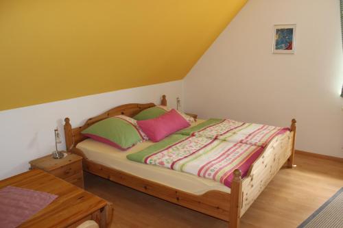 ein Schlafzimmer mit einem Holzbett mit bunten Kissen in der Unterkunft Pension-Gästehaus Küblböck in Neualbenreuth