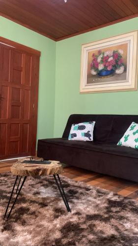 a living room with a black couch and a table at Jeitinho da Sô in Tiradentes