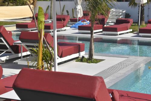 een zwembad met rode ligstoelen naast een zwembad bij Maro Apartments Arillas Corfu in Arillas