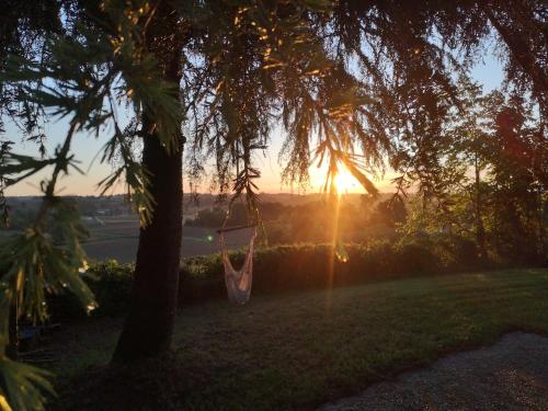 a hammock hanging from a tree with the sunset in the background at Les Trois Jolies in Maylis