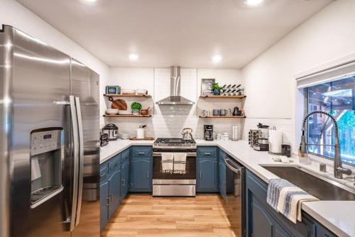 a kitchen with blue cabinets and a stainless steel refrigerator at Corlieu Falls Cabin in Sugar Pine 8 miles from Yosemite with Gazebo, Hot tub a shack and Bar top in Oakhurst
