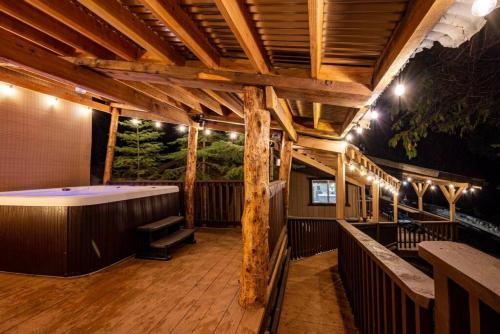 a large deck with a bath tub on a wooden floor at Corlieu Falls Cabin in Sugar Pine 8 miles from Yosemite with Gazebo, Hot tub a shack and Bar top in Oakhurst