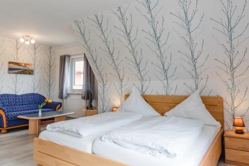 a bedroom with a bed and a blue chair at Straendhus Bed&Breakfast in Hasselberg