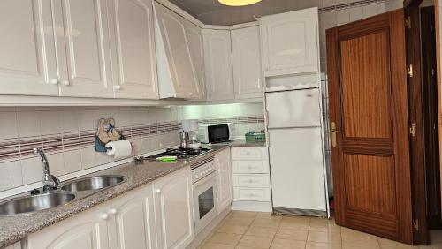 a kitchen with white cabinets and a sink and a refrigerator at CASA BLANCA-Parking gratis in Sanlúcar de Barrameda