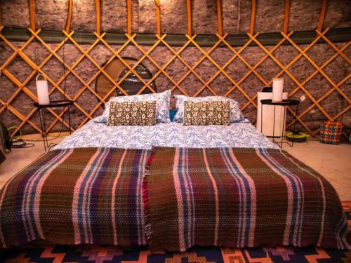 1 dormitorio con 1 cama con manta y almohadas en Giant Yurt Sleeping 8 with Spa, Catering, Walled Gardens, Nature Reserve, Free Parking en Scunthorpe