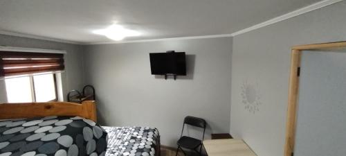 ein Schlafzimmer mit einem Bett und einem TV an der Wand in der Unterkunft EL ROBLE 2.0 CHILLAN in Chillán