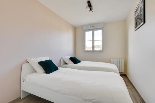 two beds in a room with white walls and a window at Appart Cosy Quartier Calme Hyper Centre Parking in Magny-le-Hongre