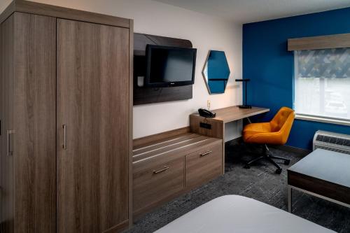 a bedroom with a desk and a tv and a cabinet at Holiday Inn Express - Charleston/Kanawha City by IHG in Charleston