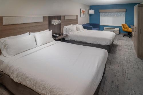 a hotel room with two beds and a chair at Holiday Inn Express - Charleston/Kanawha City by IHG in Charleston