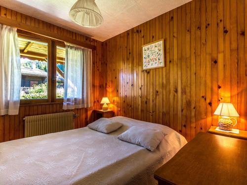 a bedroom with a bed and a wooden wall at Appartement La Clusaz, 3 pièces, 6 personnes - FR-1-437-10 in La Clusaz