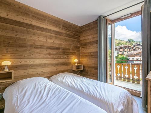 - une chambre avec un mur en bois, un lit et une fenêtre dans l'établissement Appartement 4 Pièces au Centre du Village - Proche Pistes, Wi-Fi, Parking, Balcon - FR-1-437-24, à La Clusaz