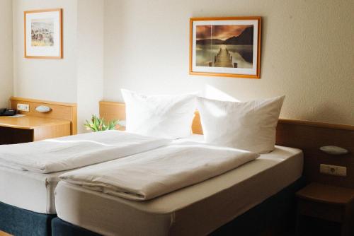 a bedroom with a bed with white sheets and pillows at Landhaus Begatal in Dörentrup