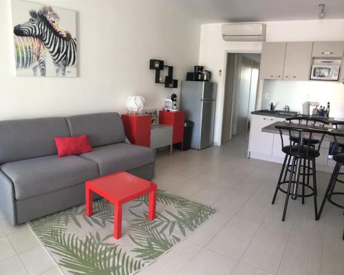 - un salon avec un canapé et un tabouret rouge dans l'établissement La Pinède Calvi, à Calvi