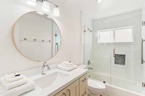 a white bathroom with a sink and a mirror at Palm Tree Oasis in Newport Beach