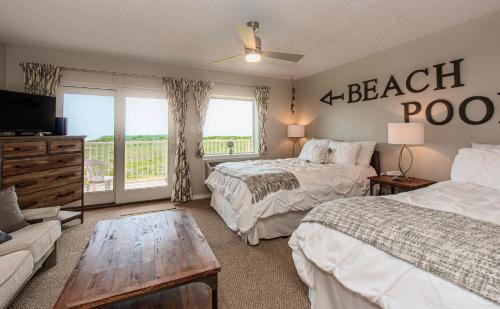 a bedroom with two beds and a couch and a table at IR149 2nd Floor Studio Condo with Gulf View, Shared Pools, Boardwalks in Port Aransas